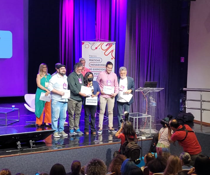 Representantes da Comissão de Orientação em Psicologia e Migração do CRP-MG sobem ao palco para receber premiação